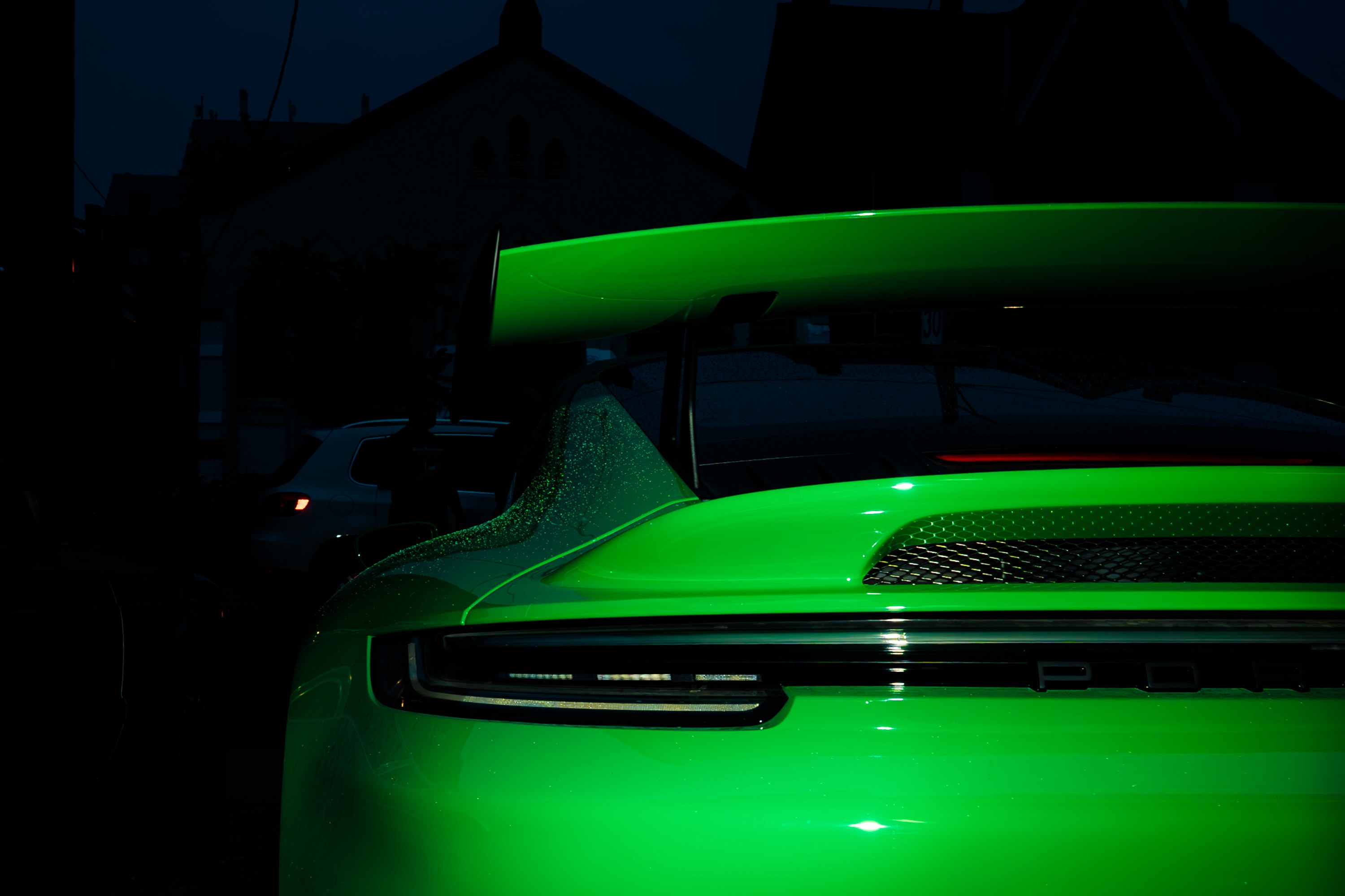 A bright green Porsche 911 parked outside the shop at dusk
