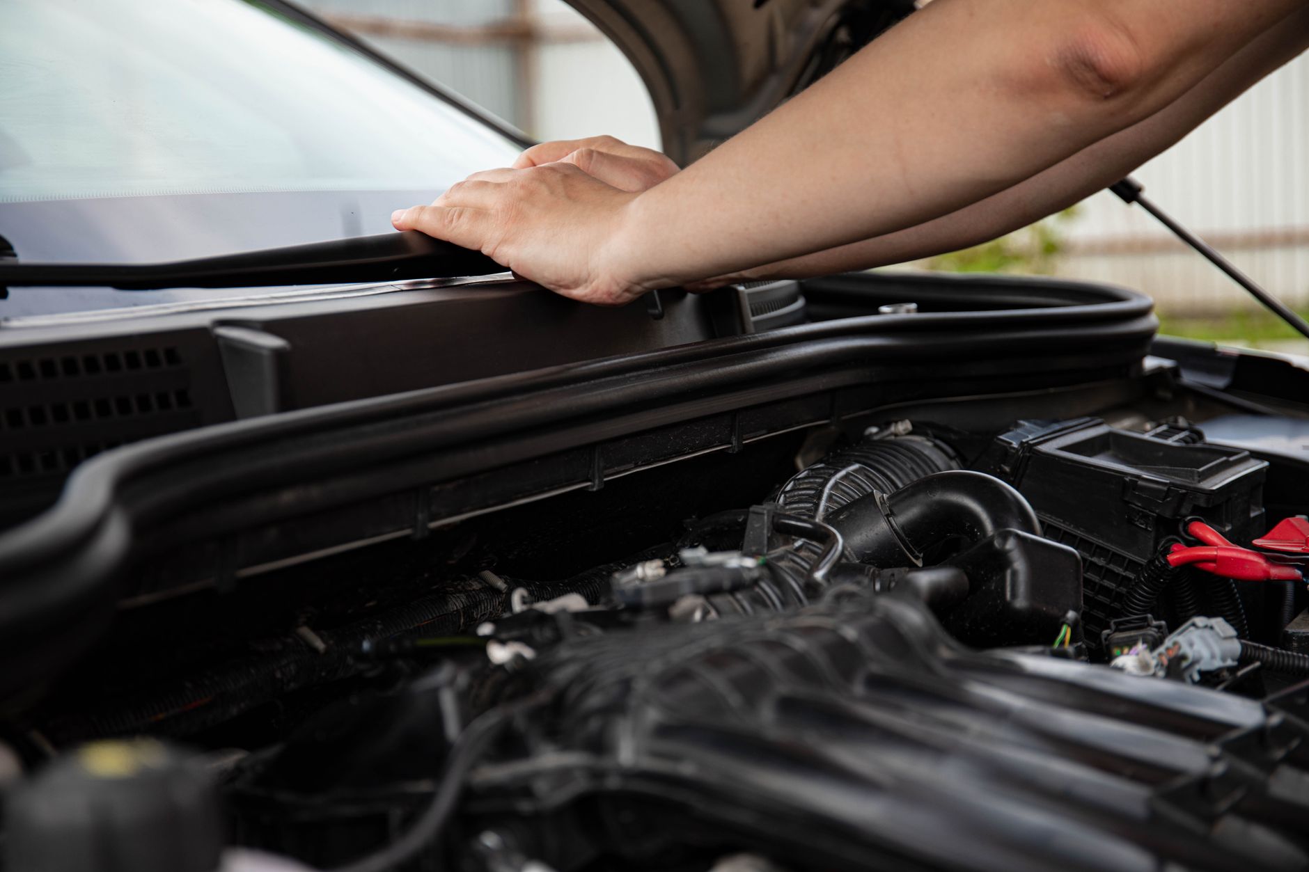 A mechanic checking under the hood of a car
